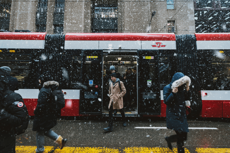 People exit a Toronto streetcar on snowy day.