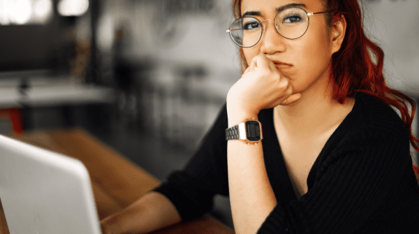 Young woman wearing glasses is thinking while she completes a personality assessment on her computer. Self awareness is key to career success.