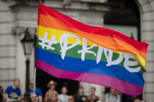 A person is holding up a pride flag to celebrate pride month events in 2024.