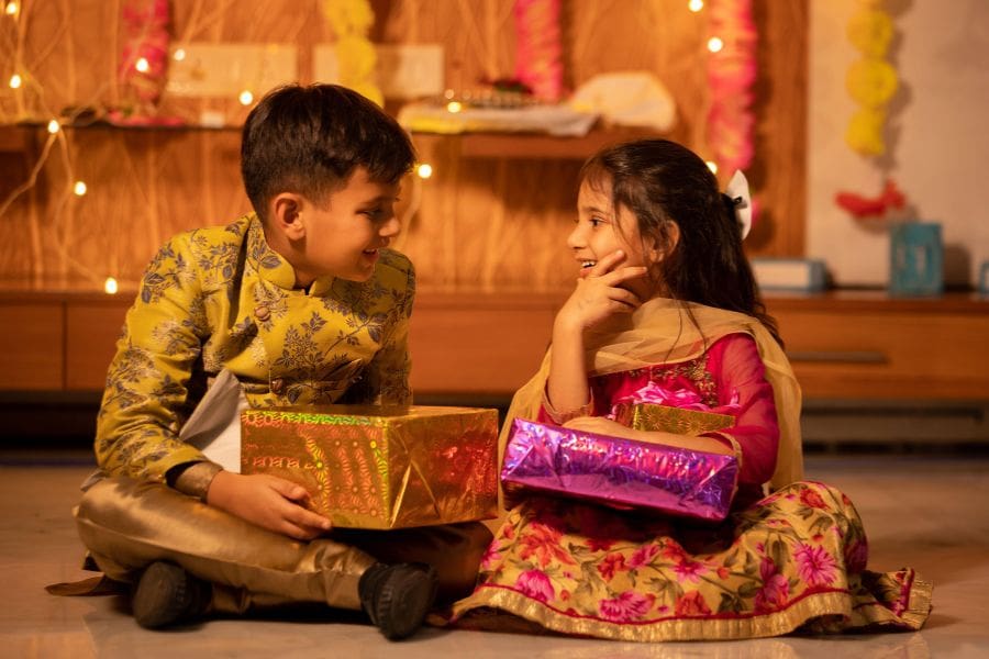 Young Indian brother and sister holding gift boxes in their hands. Celebrating Day 5 of Diwali (Bhai Dooj) and the bond between brothers and sisters.