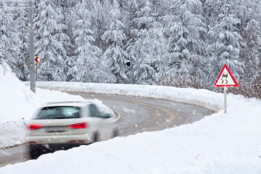 Car driving on icy, snow-covered Canadian road- example of winter driving conditions.