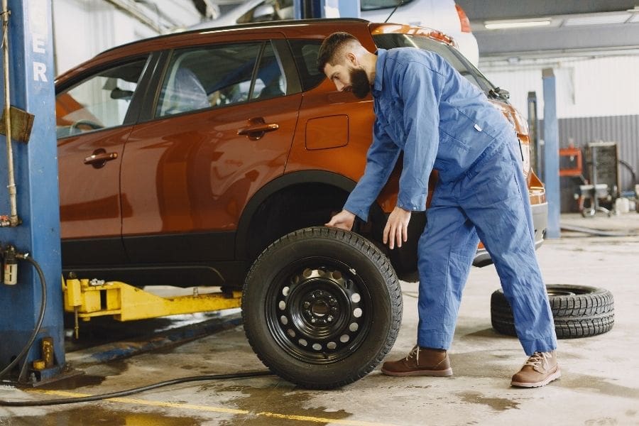 Mechanic changing tires in a Canadian auto shop to help drivers get ready for snowy and icy roads.