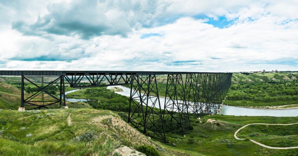 Panoramic view of the historic steel High Level Bridge spanning across the green Oldman River valley and coulees in Lethbridge, Alberta.