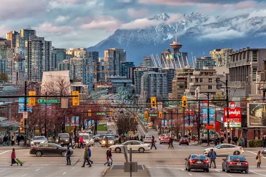 View of downtown Vancouver, BC, with mountains in the background and people enjoying outdoor spaces, representing life in Vancouver for newcomers.