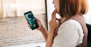 A young woman is speaking with a scam caller on her mobile phone. To avoid fraud in Canada, do not provide personal, credit card or online account details if you receive a call claiming to be from your bank or any other organization.