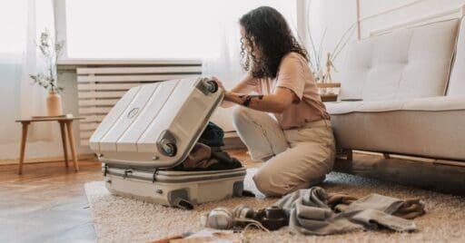 A woman is packing a suitcase and preparing to move to Canada. These Canadian financial tips can make your move less stressful and help you settle comfortably.