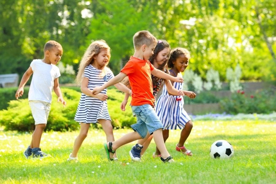 Young children a playing with a soccer ball in a neighbourhood park in Edmonton. 