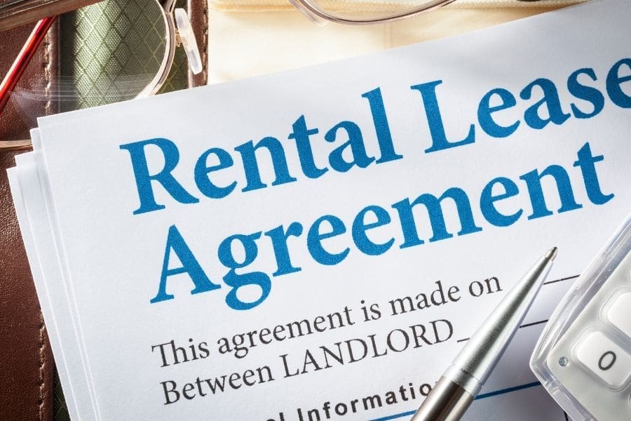 Rental lease agreements with pen and glasses on desk. 