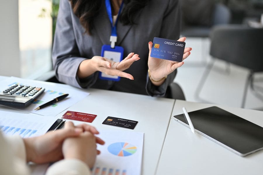 A close-up image of a female banker explaining newcomer credit card options to a customer. Getting a secured credit card is a great way to start to build credit in Canada.