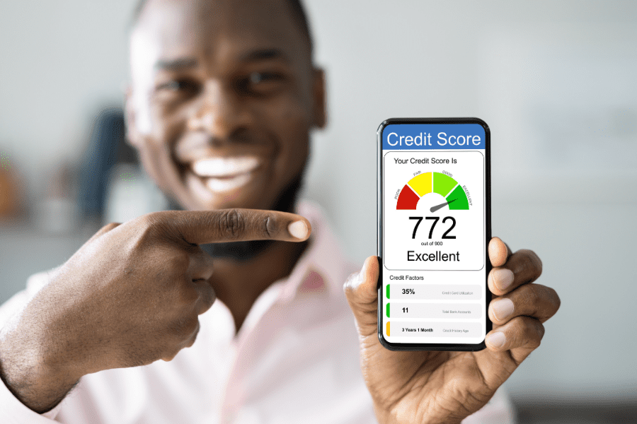 A smiling man is holding a mobile phone that is showing his 3-digit credit score ranking. 