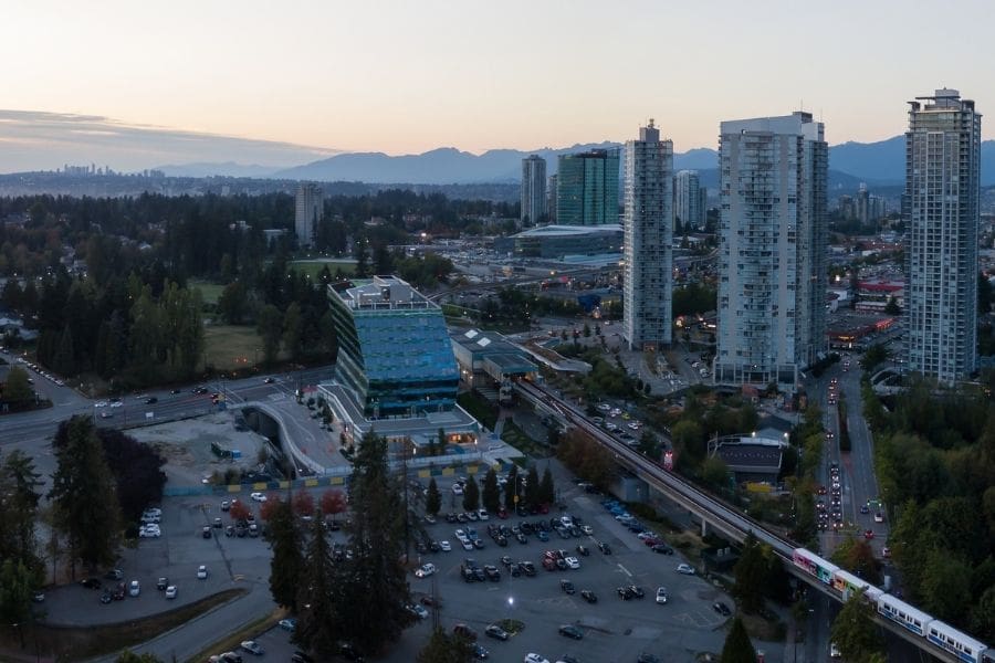 A cityscape and the Surrey Central Mall at sunset. The SkyTrain links Surrey to Vancouver, British Columbia. People can find highrise and basement apartments for rent in Surrey.