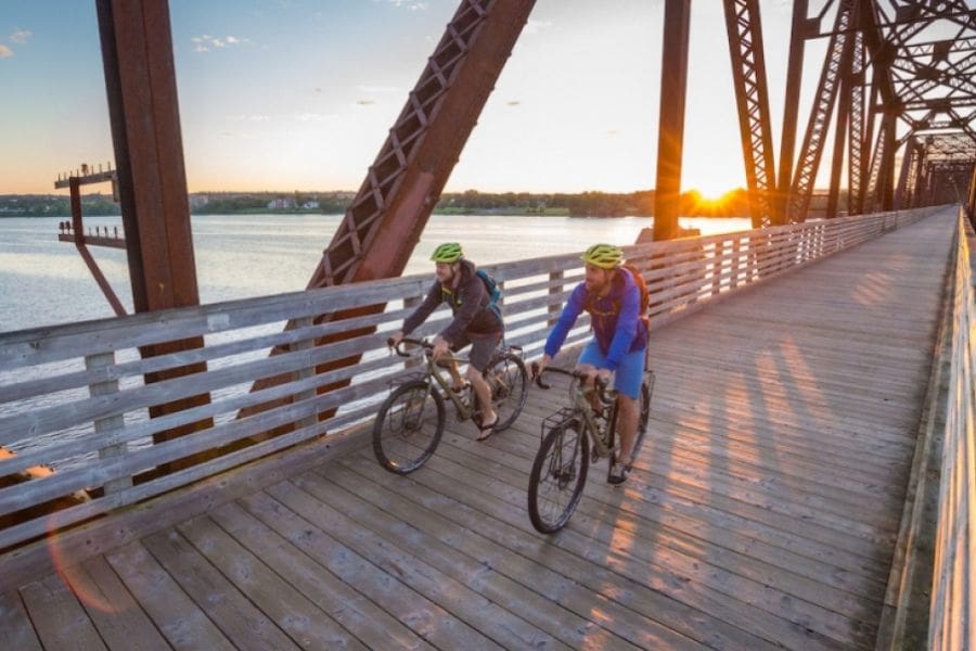 Cyclists are crossing a bridge over the Saint John River that flows through Fredericton.
