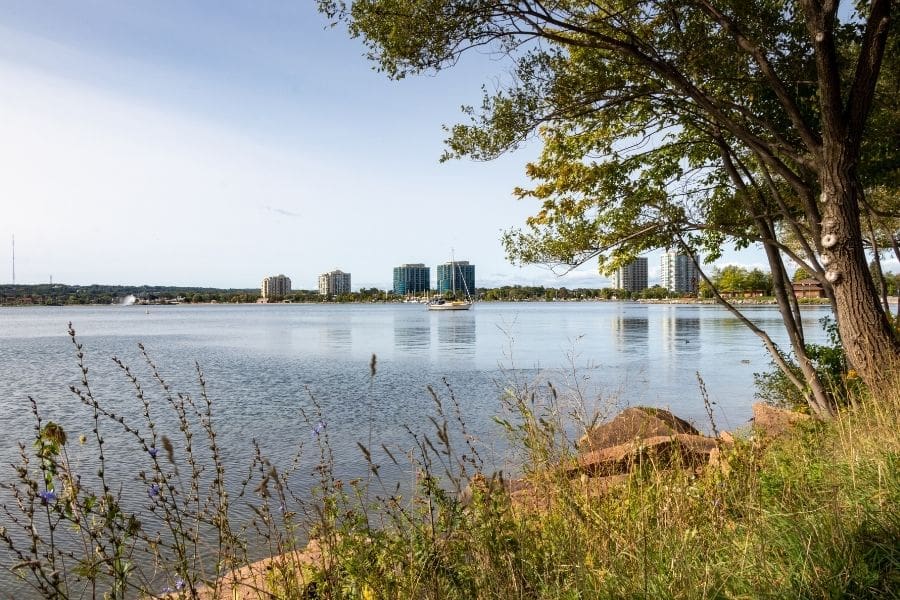 Scenic view across Kempenfelt Bay showing natural shoreline parks and high-rise condo buildings.
