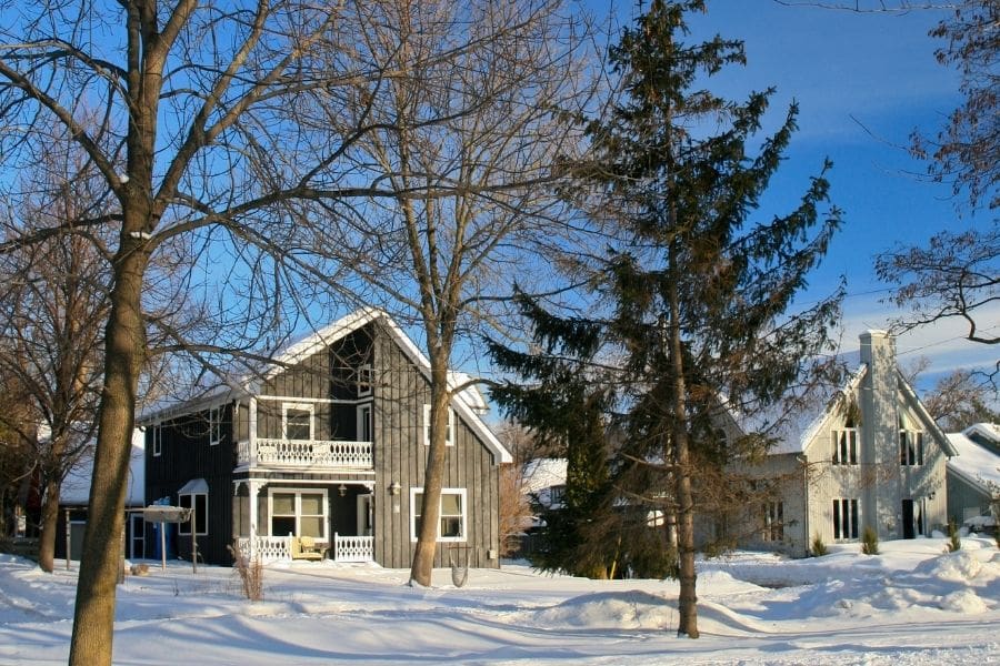 Winter scene in Barrie, Ontario, showing heritage-style homes with snow-covered yards and tall trees.