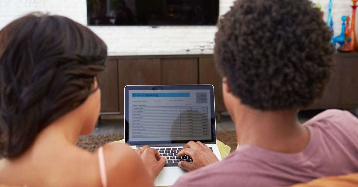 Rear view of a couple looking at online banking information and how to transfer their international credit history.