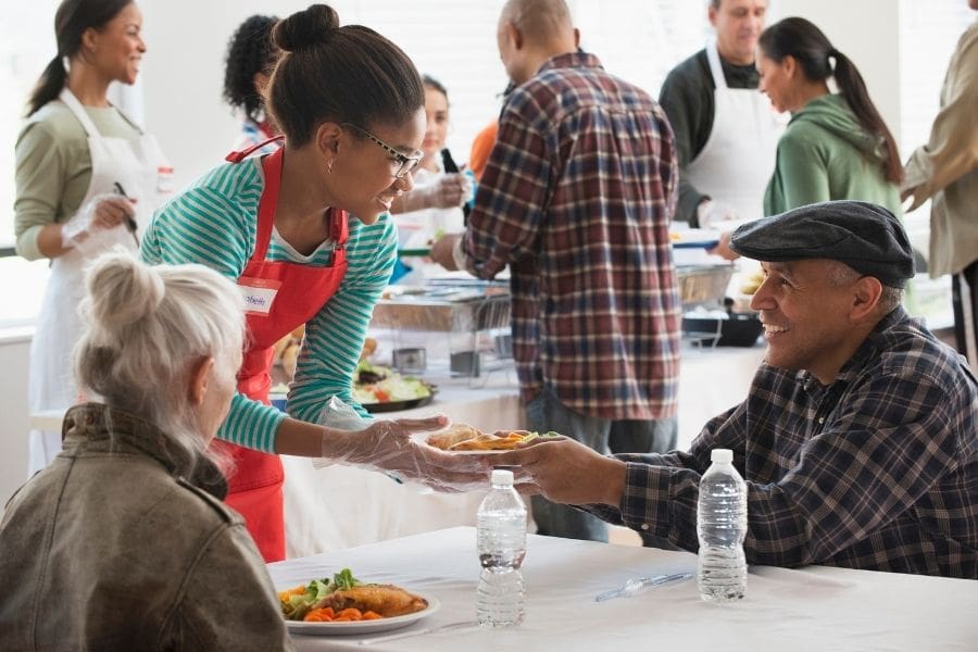 A female volunteer is serving food at a local community center.