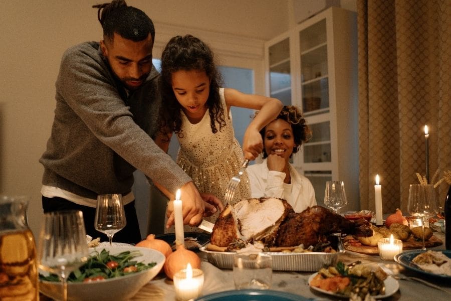 A young family are celebrating Thanksgiving in Canada and preparing to carve a traditional turkey. 