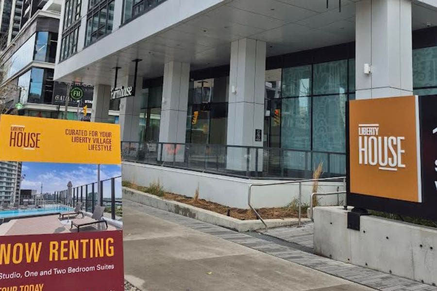 Rental apartments in downtown Toronto. A display board advertising apartments is placed in front of the entrance of the building. Renting vs buying in Canada is a big decision for newcomers. 
