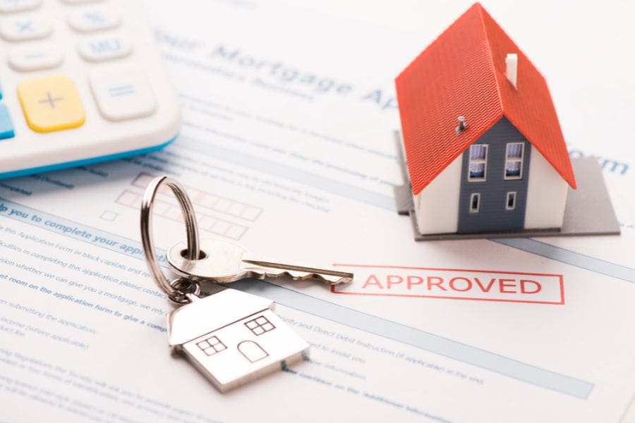 A pre-approved mortgage document with a small model home, calculator, and house keys, symbolizing the mortgage approval process.