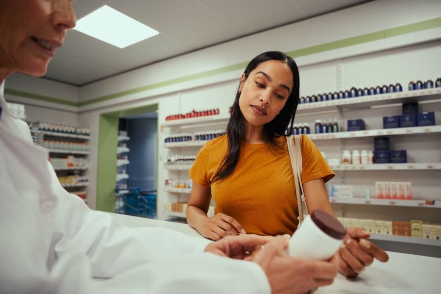 A young woman is paying for a prescription at a pharmacy.