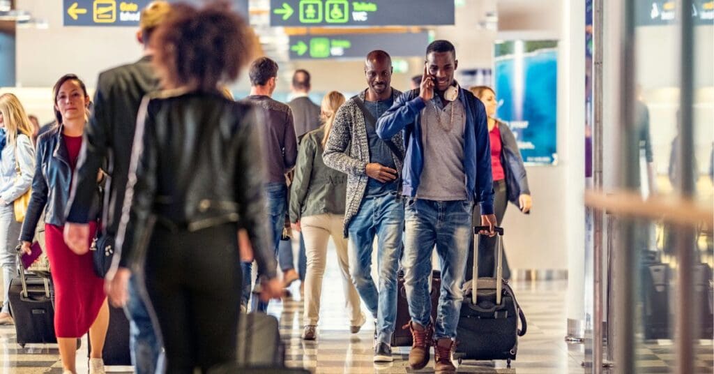 A diverse crowd of people arriving at a Canadian airport, carrying luggage and using mobile phones, representing newcomers preparing to start their life in Canada.