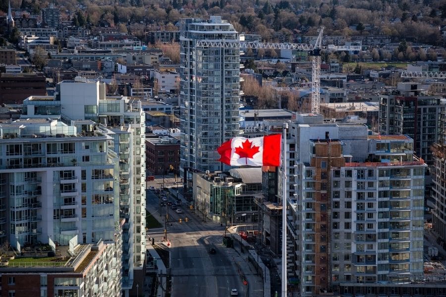 A Canadian flag stands high among rental building in Canada. 