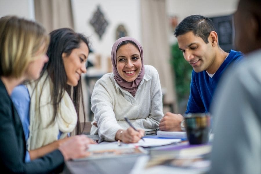 Group of newcomers seated at a table, reviewing personal finances for Canada.