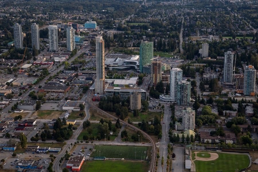 Aerial view of high-rise apartment towers and SkyTrain tracks in Surrey City Centre.
