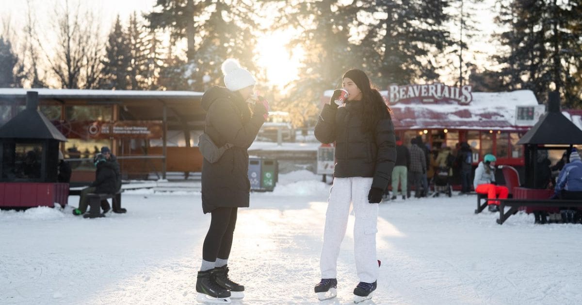 People ice skating on the Rideau Canal during Ottawa’s Winterlude festival, warming up with hot chocolate in winter.