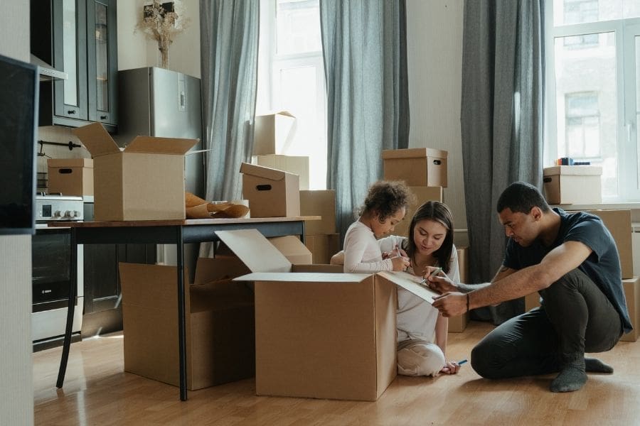 A young family unpacking boxes together in an apartment, setting up their new home after moving. 