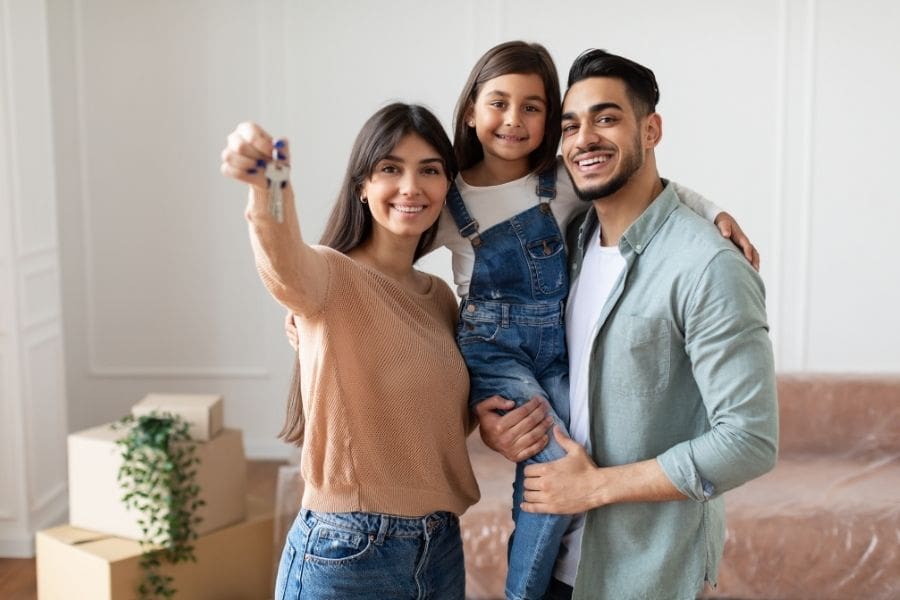 A happy newcomer family holding the keys to their new apartment, symbolizing a successful housing search.