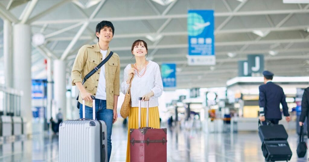 Newcomers arriving at a Canadian airport with luggage and looking happy as they begin planning their new life in Canada.