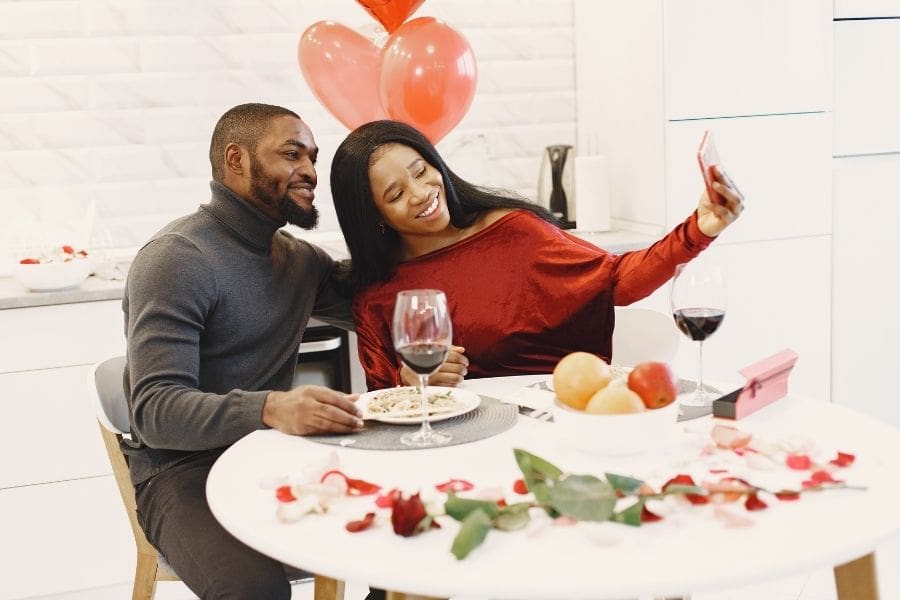 A couple is taking a selfie while enjoying a homemade dinner date at home.