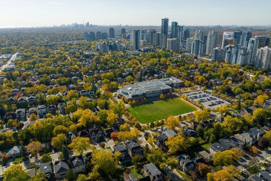 An aerial view of North York shows residential streets with a view of the downtown Toronto skyline in the distance.