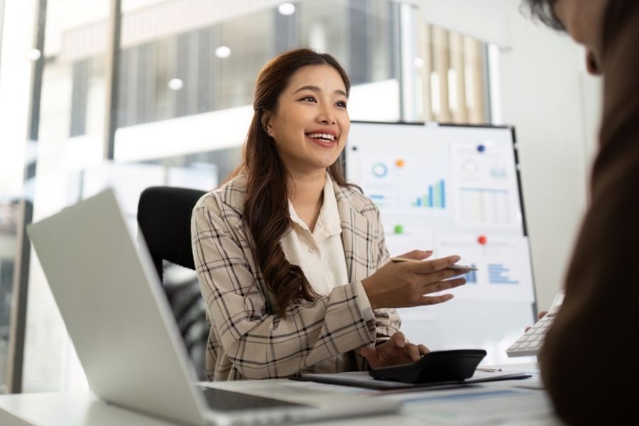 A professional woman in a business suit is discussing financial reports with a client in a modern office.