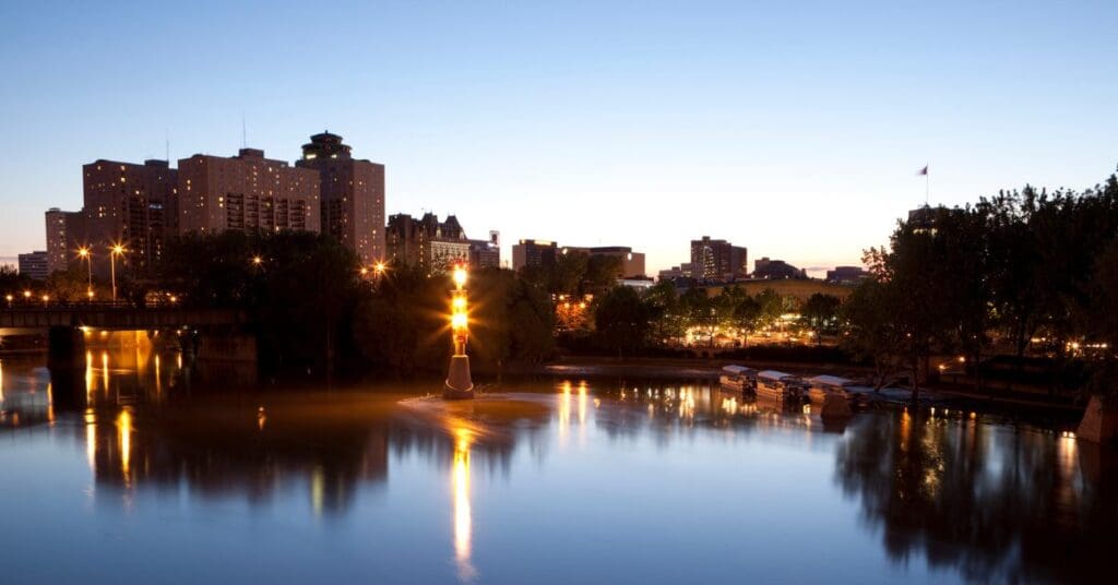 The Gateway to the West: A twilight view of Winnipeg’s historic and modern skyline reflected in the Assiniboine River.