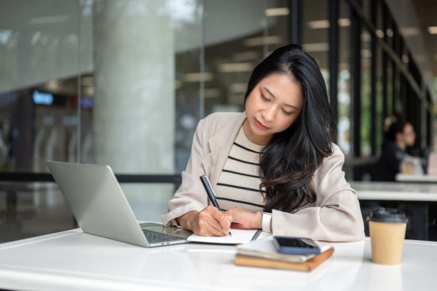 A professional woman taking notes while learning how to search for jobs in Canada on the Job Bank website.