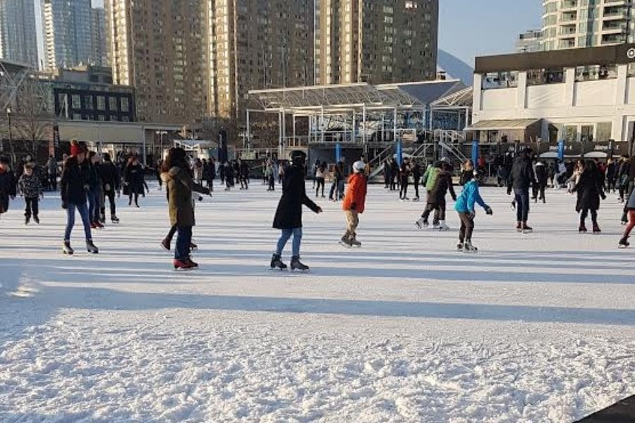 Newcomers and locals enjoying free outdoor ice skating at a municipal skating rink in Toronto.