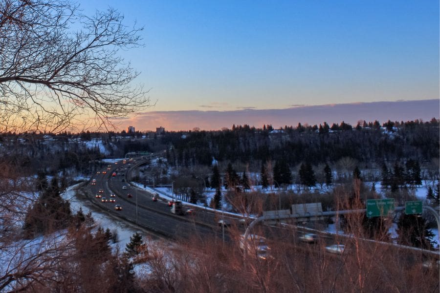 Commuters driving on Wayne Gretzky Drive in the snow during twilight, showcasing Edmonton winter road conditions.