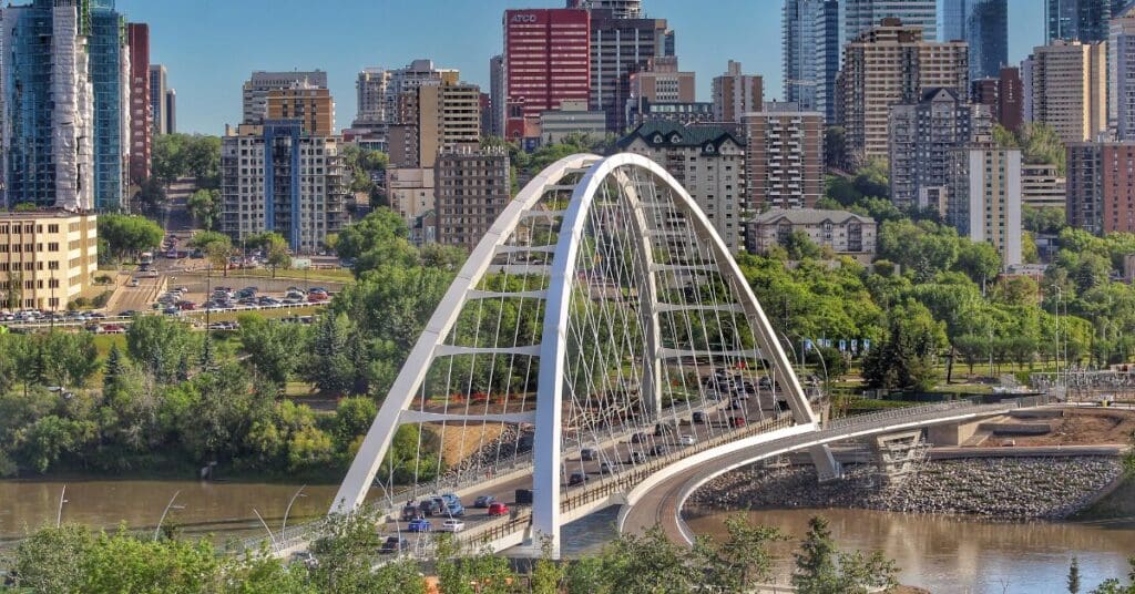 The iconic white arches of the Walterdale Bridge over the North Saskatchewan River, showcasing the vibrant downtown skyline for newcomers considering living in Edmonton.