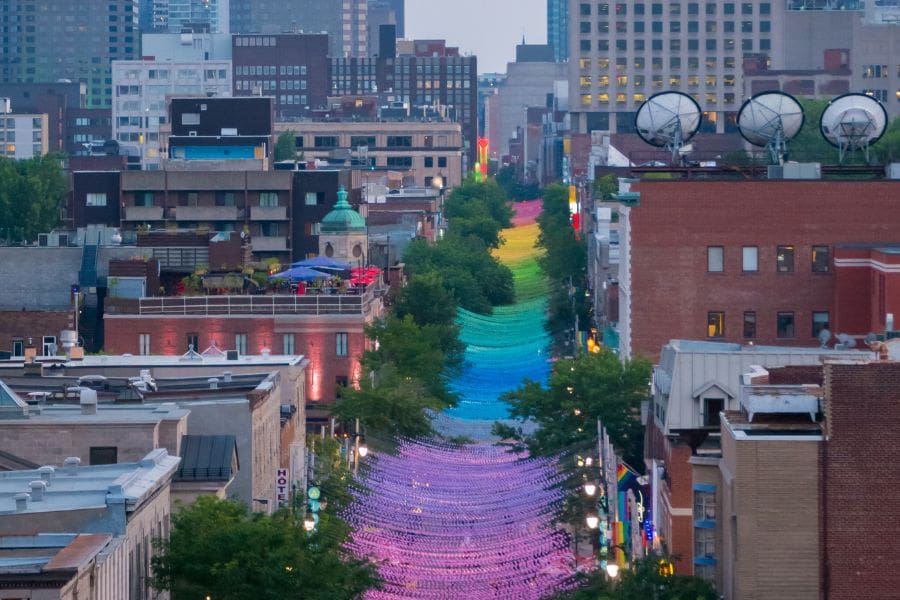 Canada Pride 2026 newcomer guide Montreal image: An elevated, street-level view of the historic multi-coloured rainbow canopy stretching over Sainte-Catherine Street East in Montreal's Gay Village