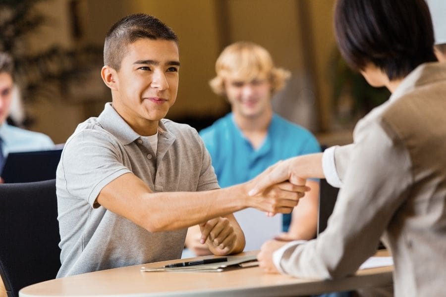 A high school student confidently shaking hands during an interview for first jobs in Canada for teens.