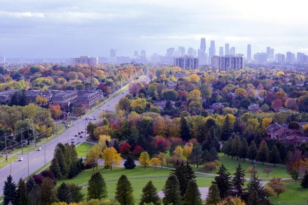 An aerial view of Mississauga looking toward the downtown city skyline in the distance. It shows residential neighbourhoods, green parks, and colouful fall foliage.