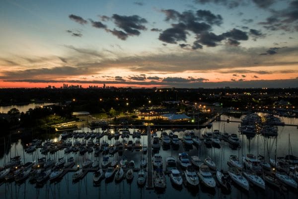 A view of the Lakefront Promenade Marina in Mississauga filled with boats at sunset. The Toronto skyline is visable in the distance.
