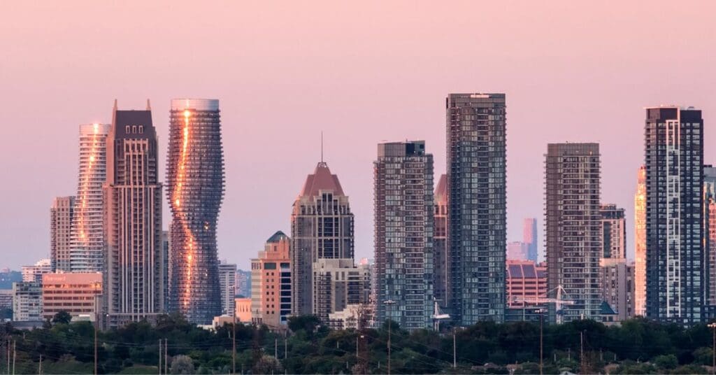 The twisting Absolute World condominium towers in downtown Mississauga are reflecting golden sunlight against a pink sky.