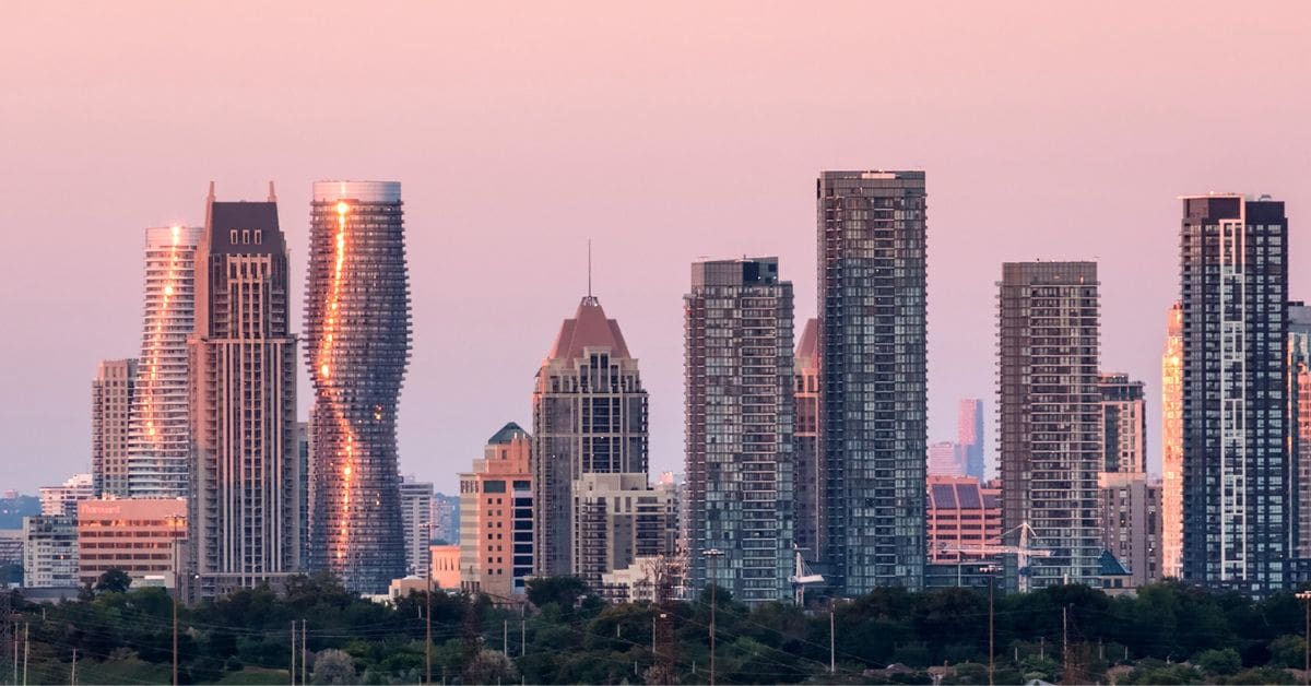 The twisting Absolute World condominium towers in downtown Mississauga are reflecting golden sunlight against a pink sky.