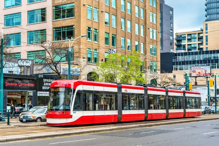 A red and white TTC streetcar operating on Spadina Avenue, showing the accessible public transit options available in Toronto, ON.