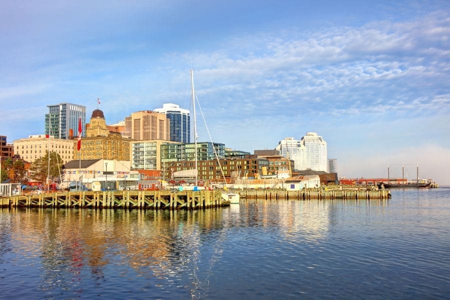 A sunny view of the Halifax Waterfront boardwalk, wooden piers, and city skyline in Nova Scotia during summer.