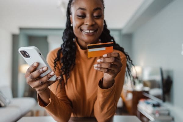 A newcomer using a smartphone and payment card to complete Canadian bank setup and 2FA authentication.