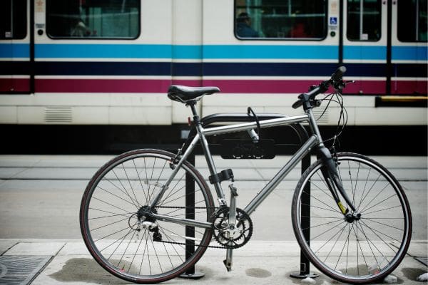 A bicycle locked to a bike rack in front of a Calgary Transit CTrain.